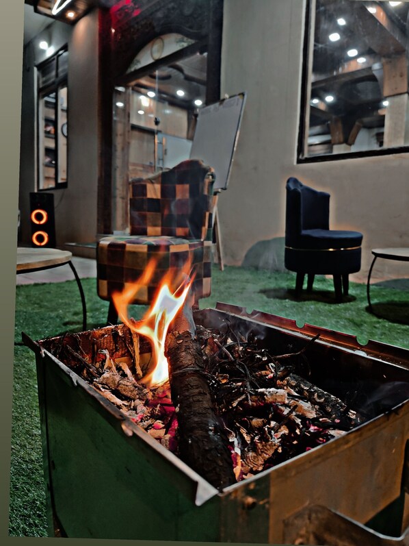 Cozy seating area with a warm fire pit and modern industrial design.