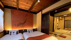 Una habitación de hotel con dos camas, un tapiz grande en la pared y una puerta corredera que da a otra habitación.