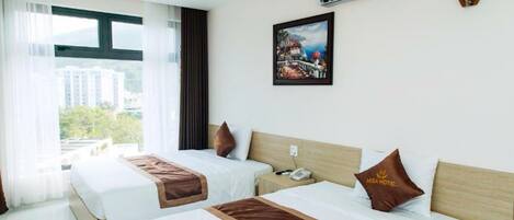 Habitación de hotel con dos camas, un ventanal grande, un equipo de aire acondicionado y un cuadro en la pared.