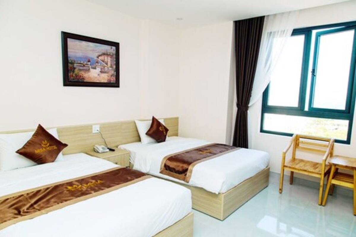 A hotel room with two beds, a desk, and a chair.