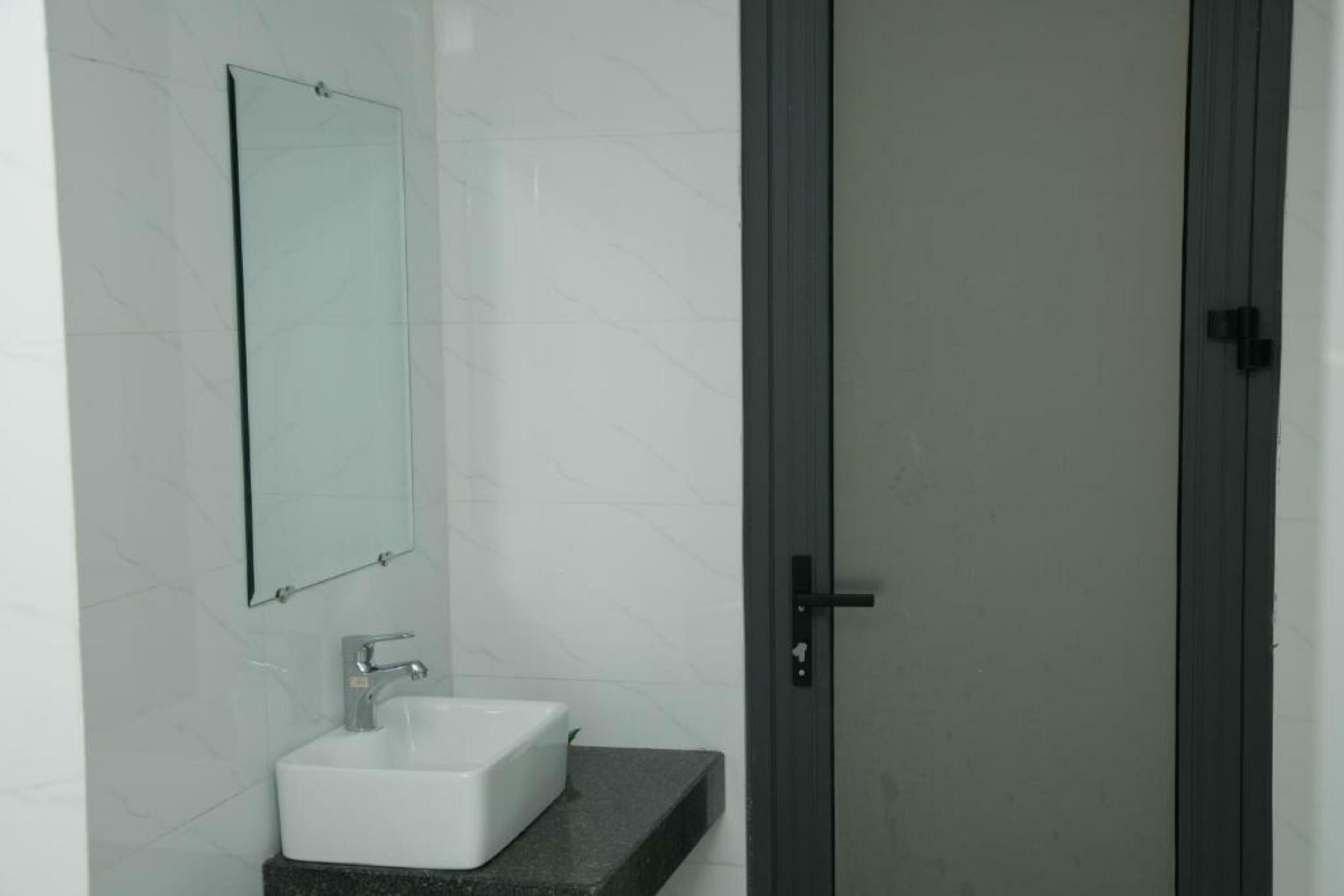 A bathroom with a white sink, a mirror, and a door.