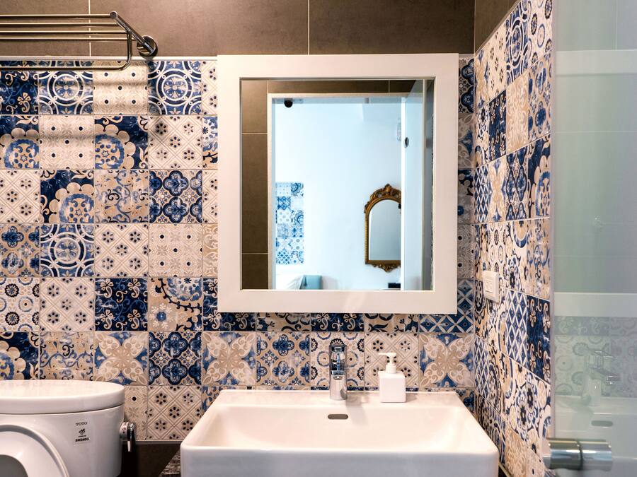 A bathroom with a sink, mirror, and patterned tiles.