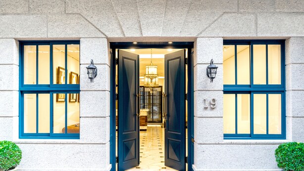 Une entrée d’immeuble avec une porte à deux battants, un lustre et le chiffre « 19 » peint sur le mur.