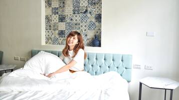 A hotel room with a bed, a small table, and a wall with a decorative tile pattern.
