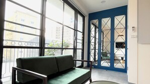Un salon moderne avec un canapé vert, une table ronde et de grandes fenêtres donnant sur la ville.