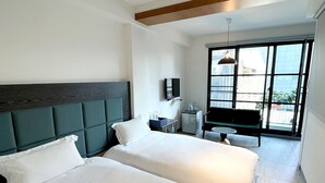 Une chambre d’hôtel avec deux lits, un petit bureau, une chaise, une télévision et un balcon avec vue.