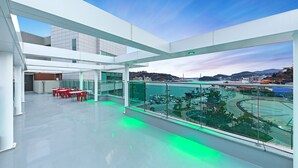 A spacious indoor area with a glass railing overlooking a parking area and a body of water. - I Stayed Pension Yeosu (Yeosu)