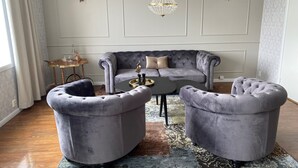 A living room with a grey sofa, two armchairs, a coffee table, and a chandelier. - Björkudden Hotell & Restaurang (Sandoverken)