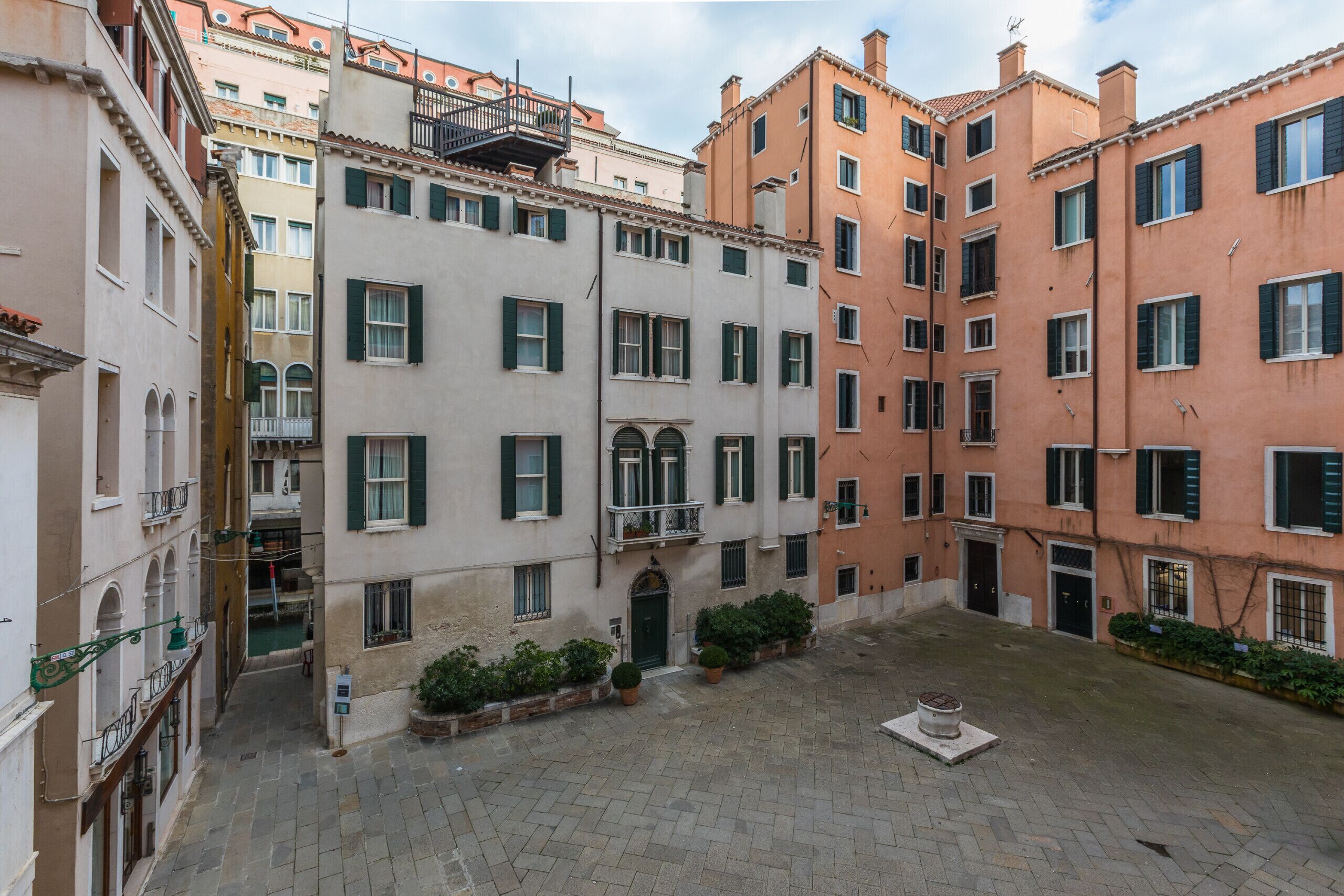 Une cour intérieure avec une fontaine centrale, entourée d’immeubles dotés de balcons et de fenêtres.