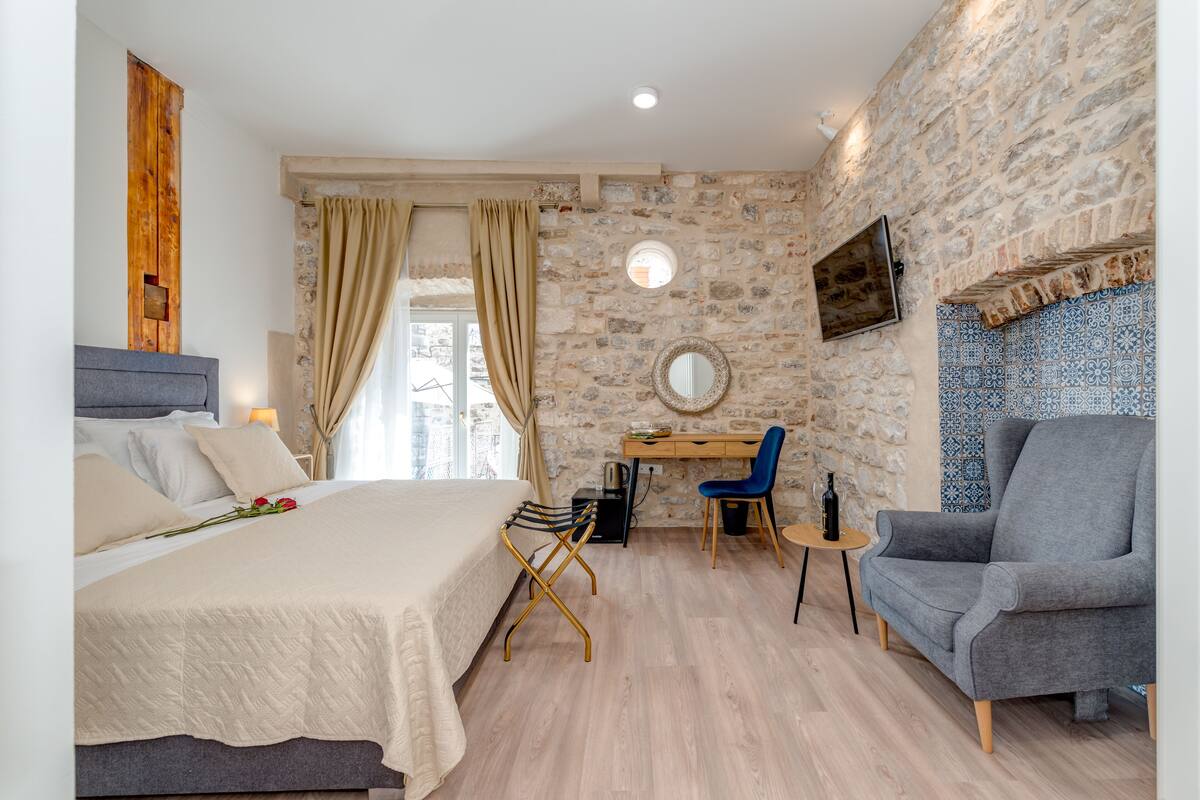 A bedroom with a bed, a desk, a chair, and a TV.