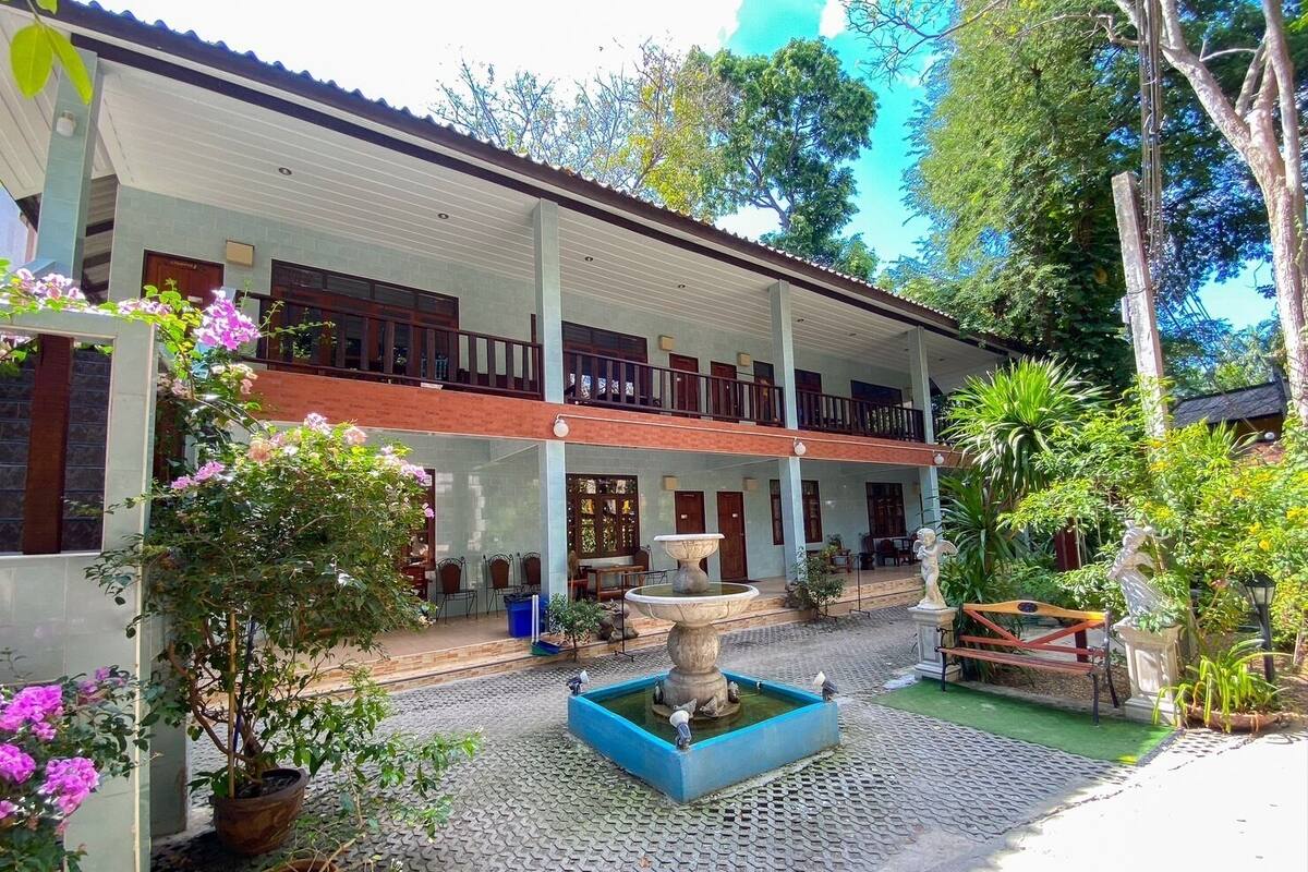 A two-story building with a covered patio area, outdoor seating, and a central water feature.