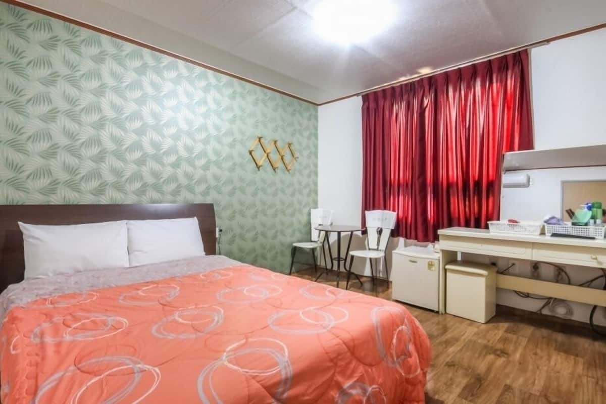 Un dormitorio con una cama, un escritorio, una silla y una cortina roja.