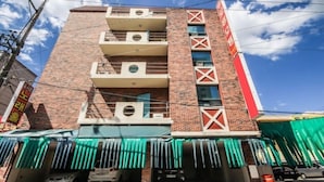 A multi-story building with a brick facade, balconies, and a green awning over the entrance. - Royal Motel (Gwangju)