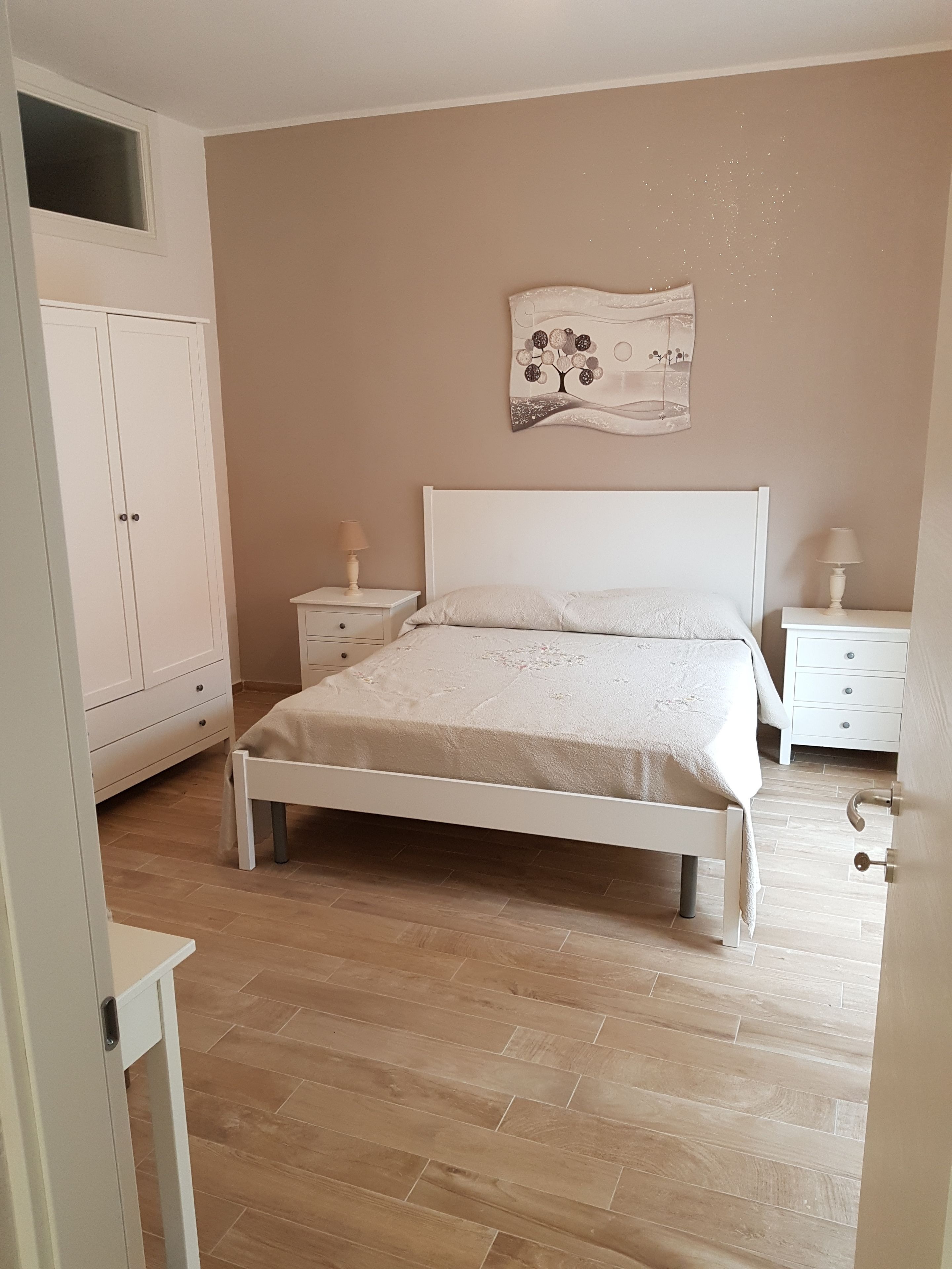 Ein Schlafzimmer mit einem Bett, zwei Nachttischen, einem Kleiderschrank und einem Wandbild.