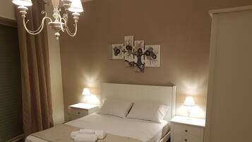 A neatly arranged bedroom with a bed, two bedside tables with lamps, a chandelier, and wall art.