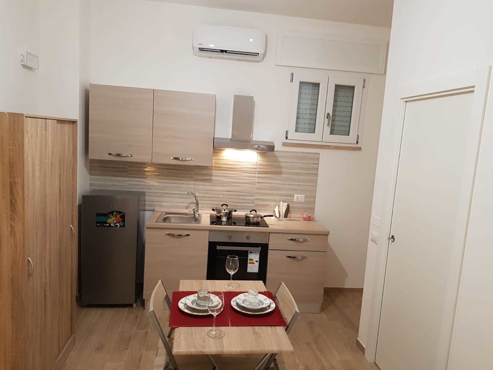 A compact kitchen with a built-in oven, a sink, and a dining table set for two.