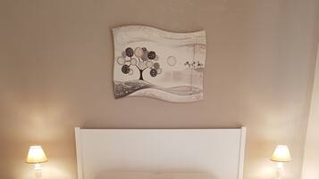 A bedroom with a bed, two bedside tables, and a wall-mounted artwork.