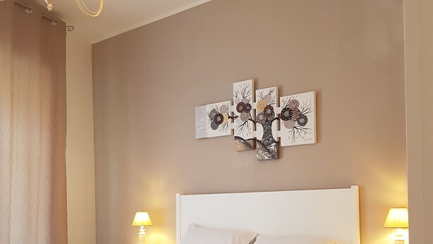 Una camera da letto ordinata con un letto, comodini e un lampadario.