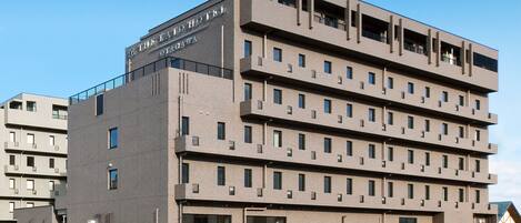 A multi-story hotel with a modern design, featuring balconies on each floor and a flat roof.