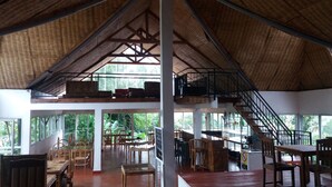 A spacious indoor area with a high ceiling, wooden furniture, and a staircase leading to an upper level.