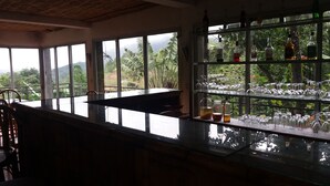 A bar area with a view of lush greenery and mountains through large windows.