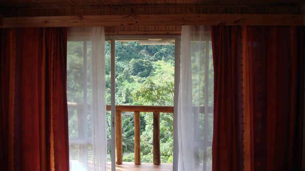 A room with a wooden ceiling and a large window with red curtains.