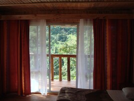 Una habitación con techo de madera y un ventanal con cortinas rojas.