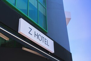 Une enseigne d’hôtel portant le nom « Z HOTEL » est fixée à la façade d’un immeuble.