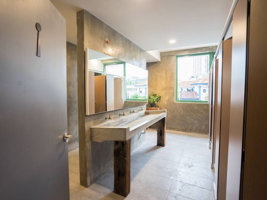 Een moderne badkamer met een grote spiegel, een betonnen wasbak en uitzicht op gebouwen.
