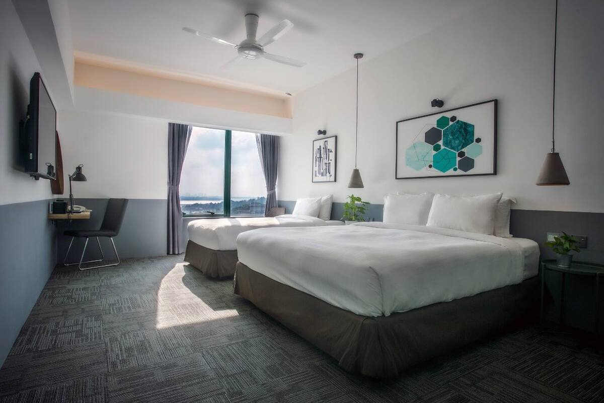 A modern hotel room with a large bed, a desk, and a view of the city.