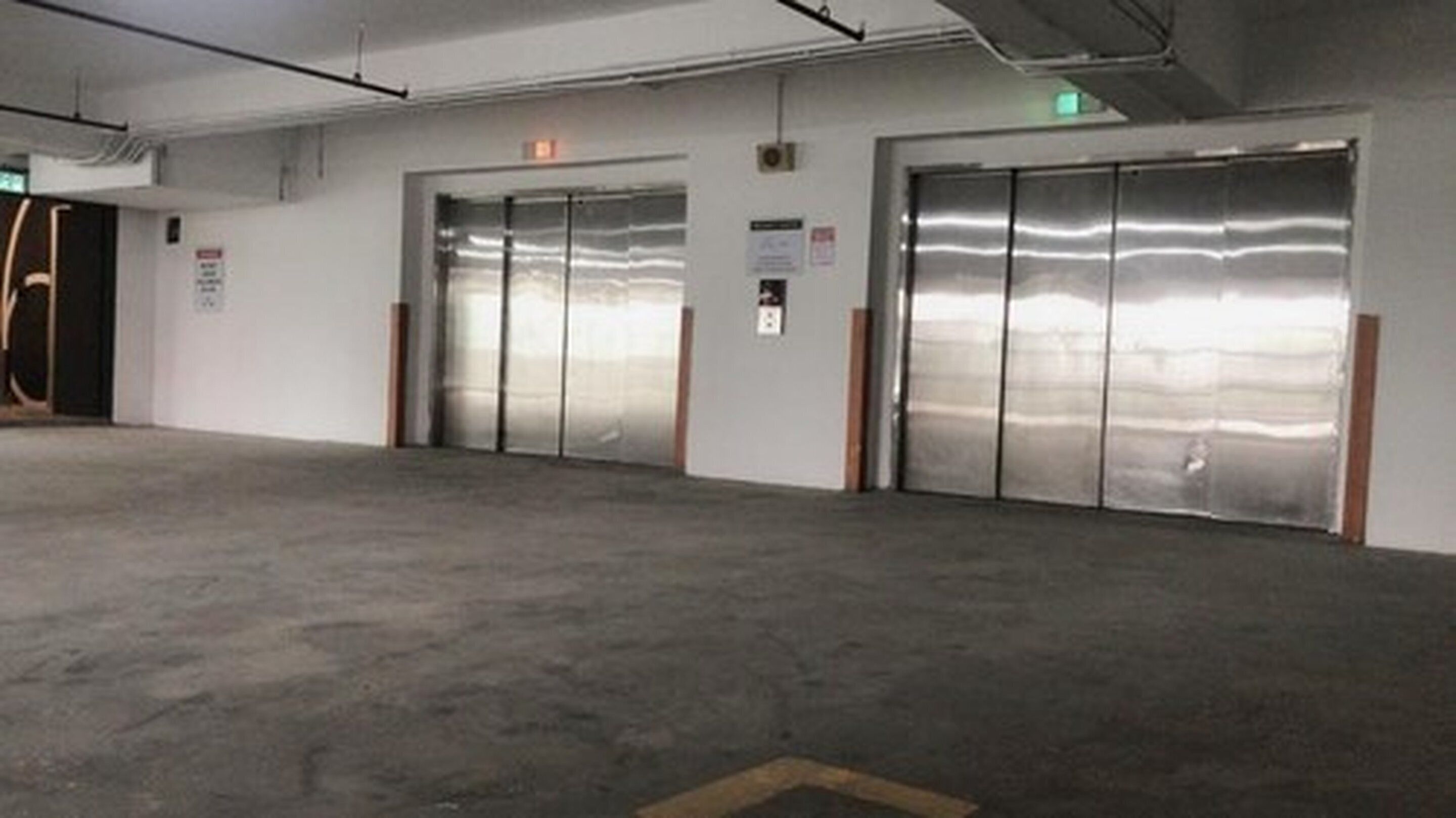 A clean, empty parking garage with two large, metallic elevator doors and a concrete floor.