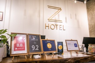 Zona de recepción de un hotel con premios enmarcados por la satisfacción del cliente y un gran letrero Z HOTEL.