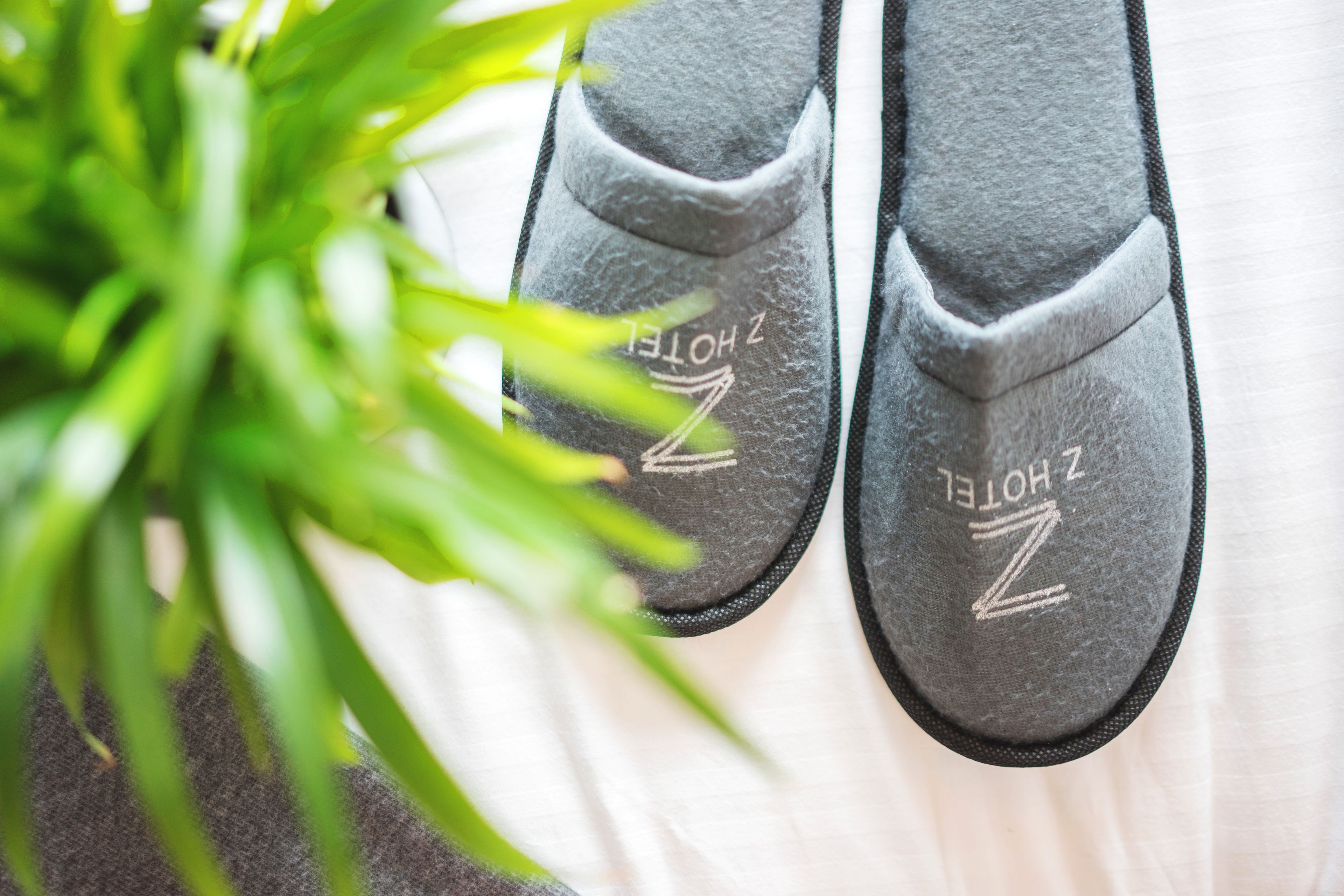 A pair of black slippers with the text "ZHOTEL" on them.