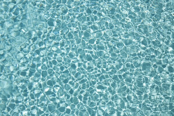 A close-up of clear, blue water with a pattern of light reflections.