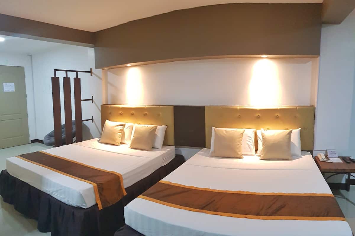 Une chambre d’hôtel avec deux lits, chacun doté d’une tête de lit, d’une table de chevet et d’un téléphone.
