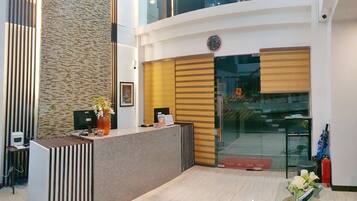 A modern reception area with a reception desk, a clock, and a glass door leading to the entrance.