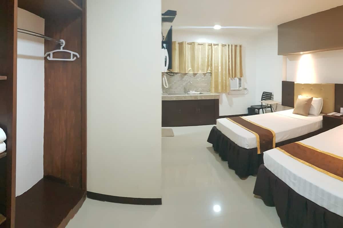 Une chambre d’hôtel avec deux lits, une armoire, un bureau et une salle de bain.