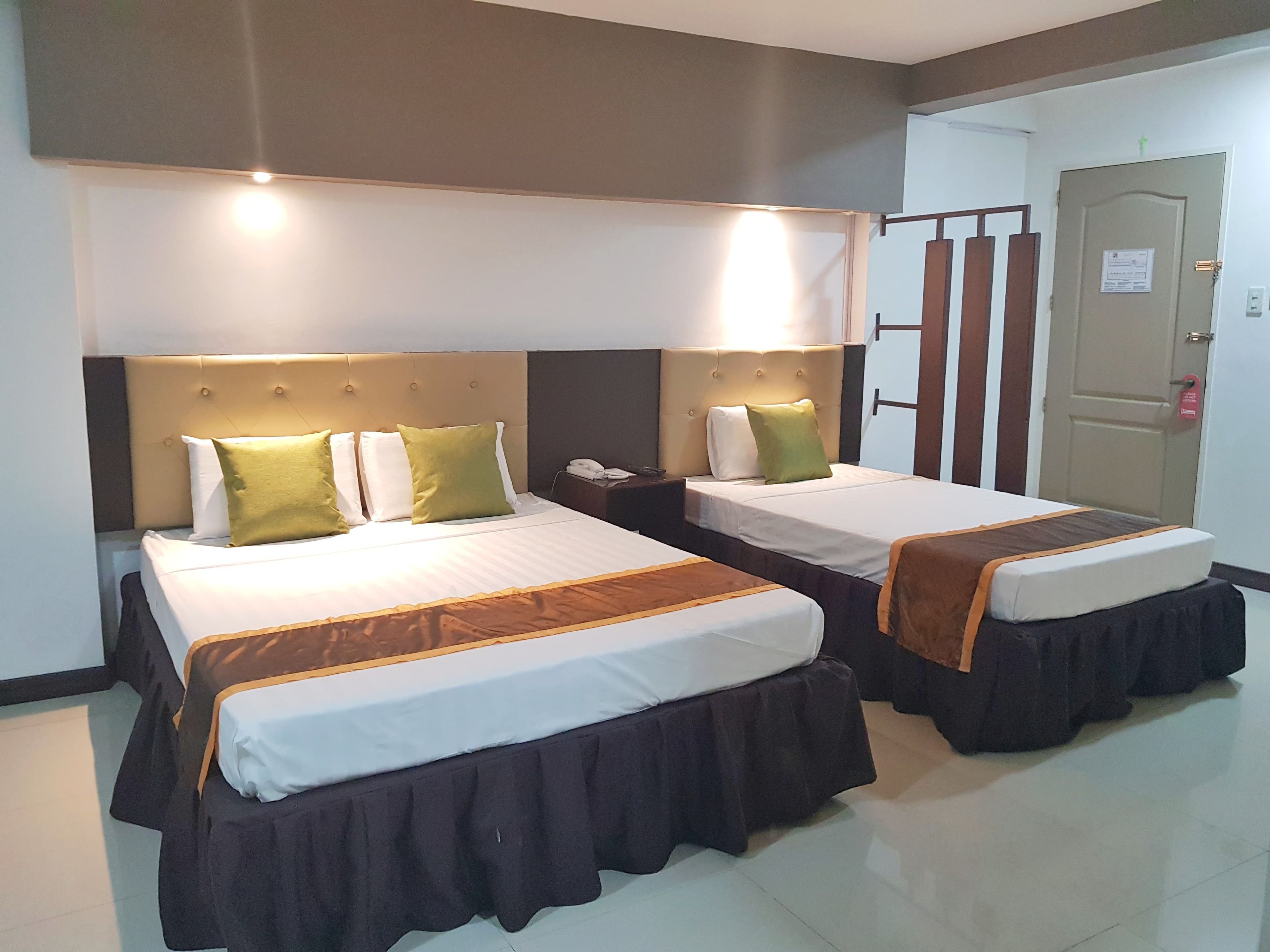 A hotel room with two beds, each with a headboard, bedside tables, and a telephone.