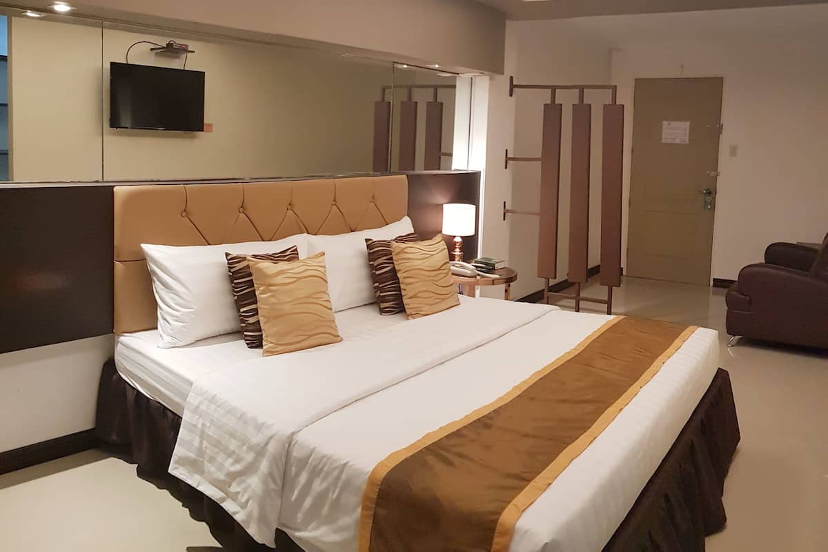 Une chambre d’hôtel avec un grand lit, un téléviseur fixé au mur et une porte avec une pancarte.