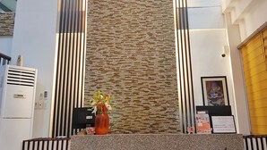 A reception area with a modern design, featuring a textured wall, vertical blinds, and a hanging light fixture. - North Tourist Inn (Bacolod)