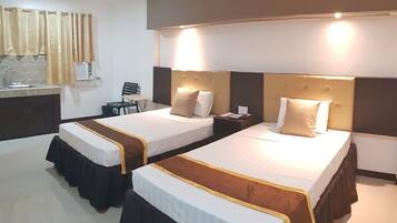 A hotel room with two beds, a desk, a chair, and a window with curtains.