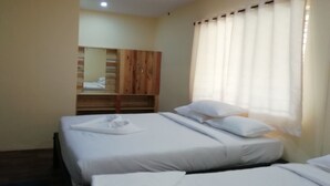 Habitación de hotel con dos camas, un armario de madera y una ventana con cortinas.