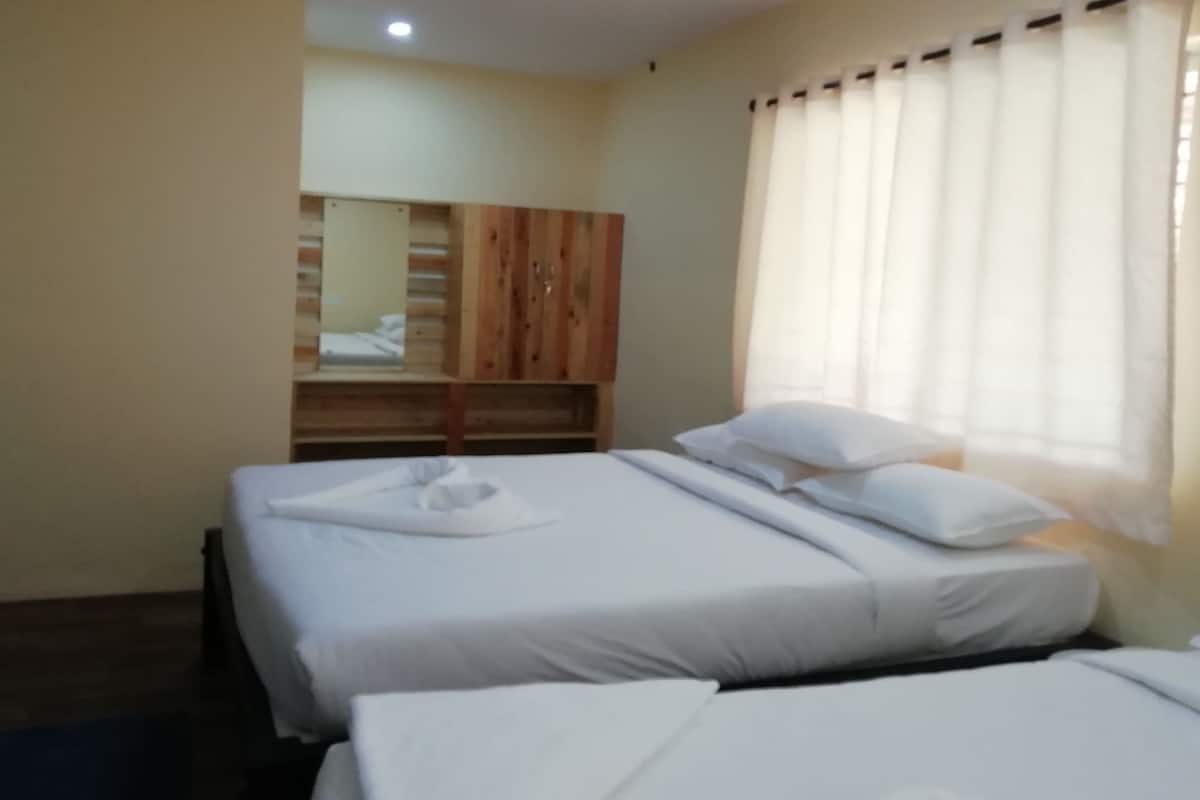Habitació d'hotel amb dos llits, un armari de fusta i una finestra amb cortines.