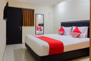 Habitación de hotel con una cama, una puerta negra, un espejo y una ventana con cortinas marrones.