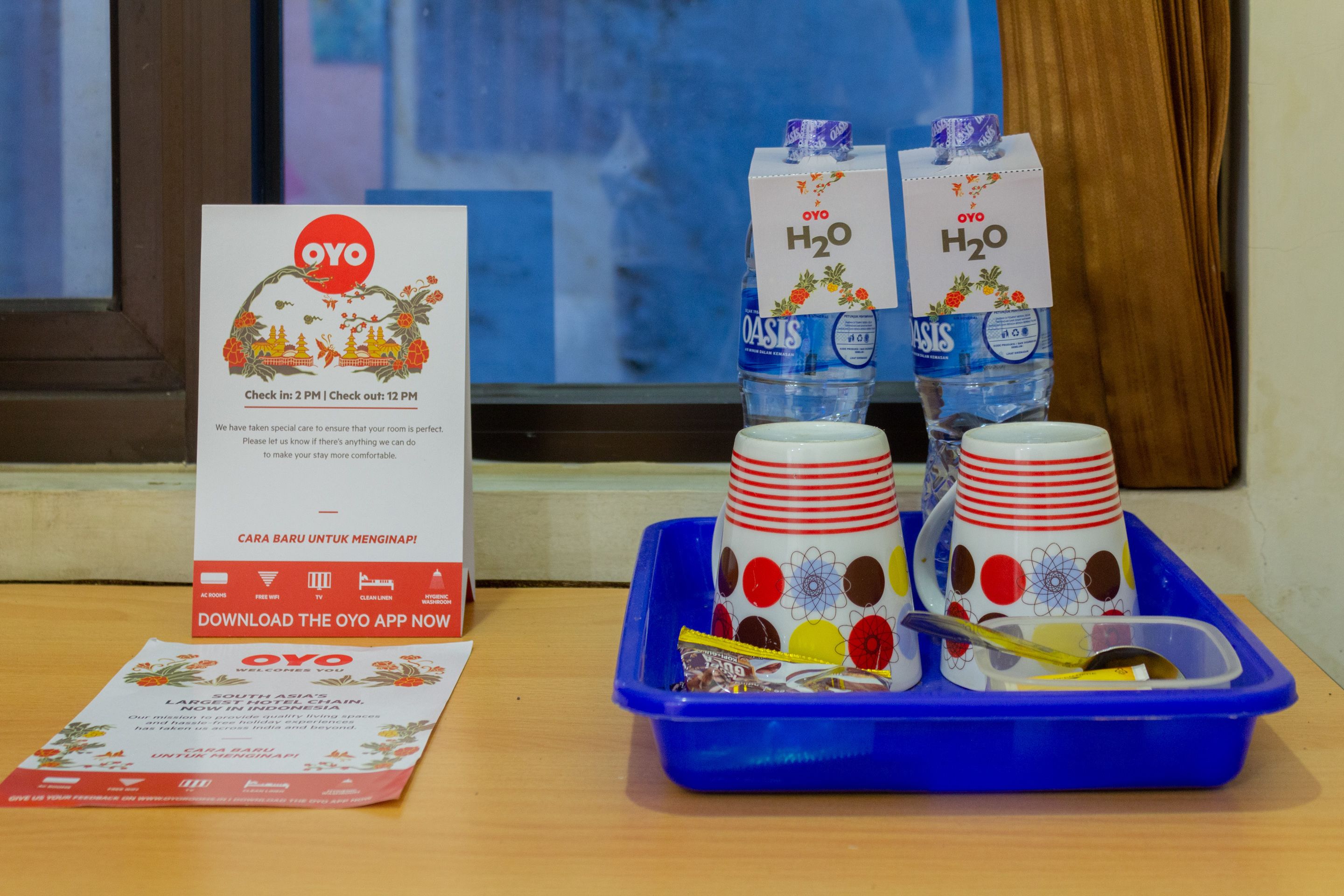 A table with a sign, two water bottles, and a tray with cups and a spoon.