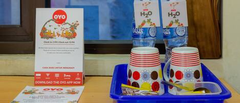 A table with a sign, two water bottles, and a tray with cups and a spoon.