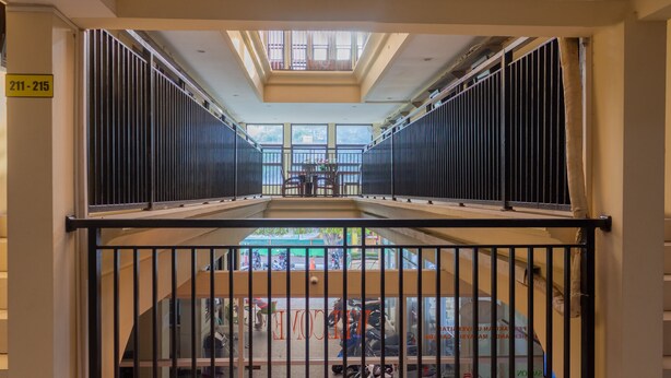 A corridor with a metal railing, a skylight, and a view of a street below. - Capital O 989 Audah Guesthouse Syariah (Jakarta)