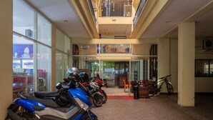 A multi-level building with a glass storefront, a reception area, and several motorcycles parked inside. - Capital O 989 Audah Guesthouse Syariah (Jakarta)