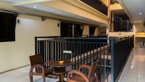 A dining area with a round table and four chairs, a black railing, and a staircase leading to an upper level. - Capital O 989 Audah Guesthouse Syariah (Jakarta)