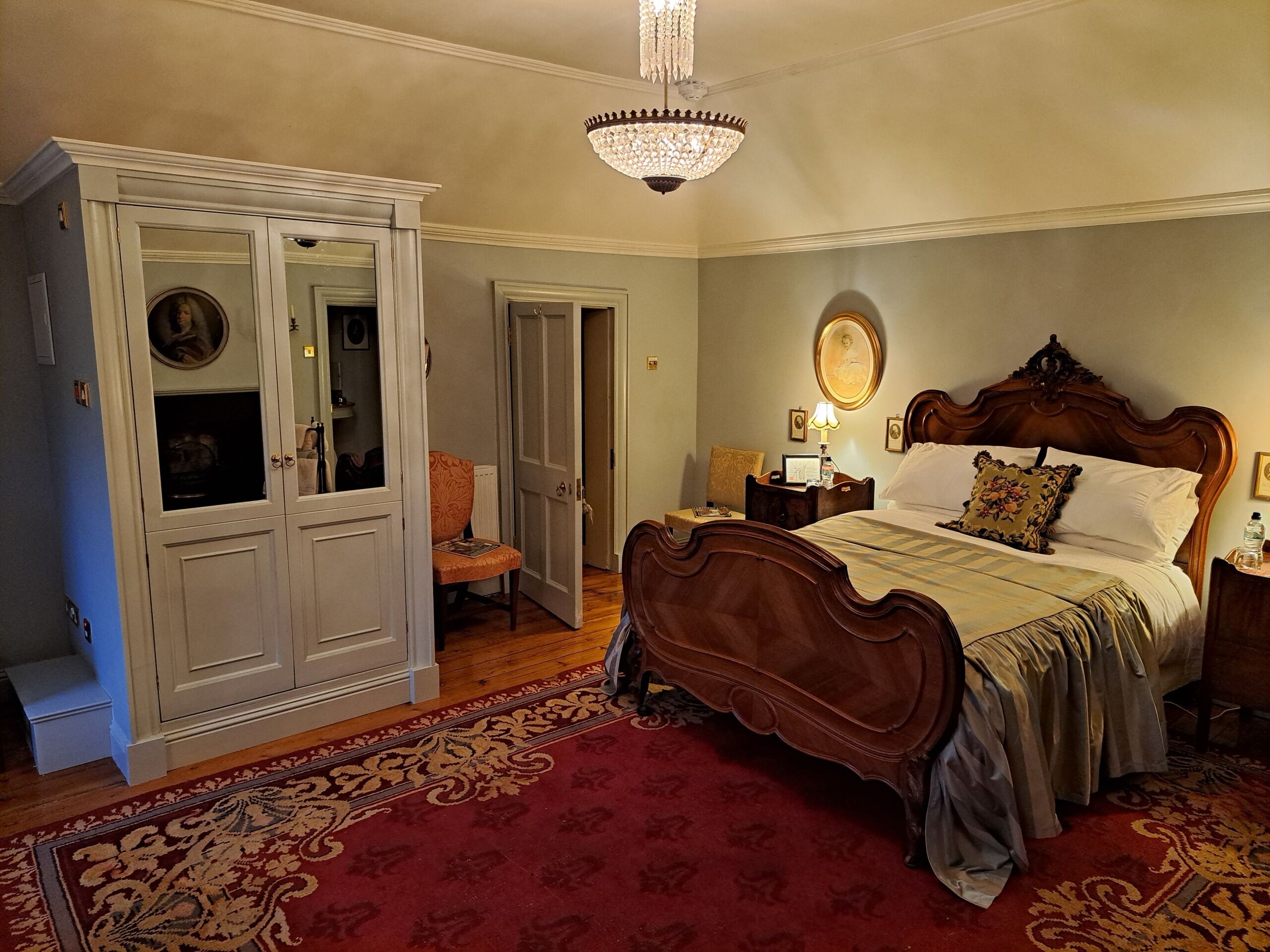 Une chambre à coucher avec un grand lit, une armoire, un lustre et une moquette rouge.